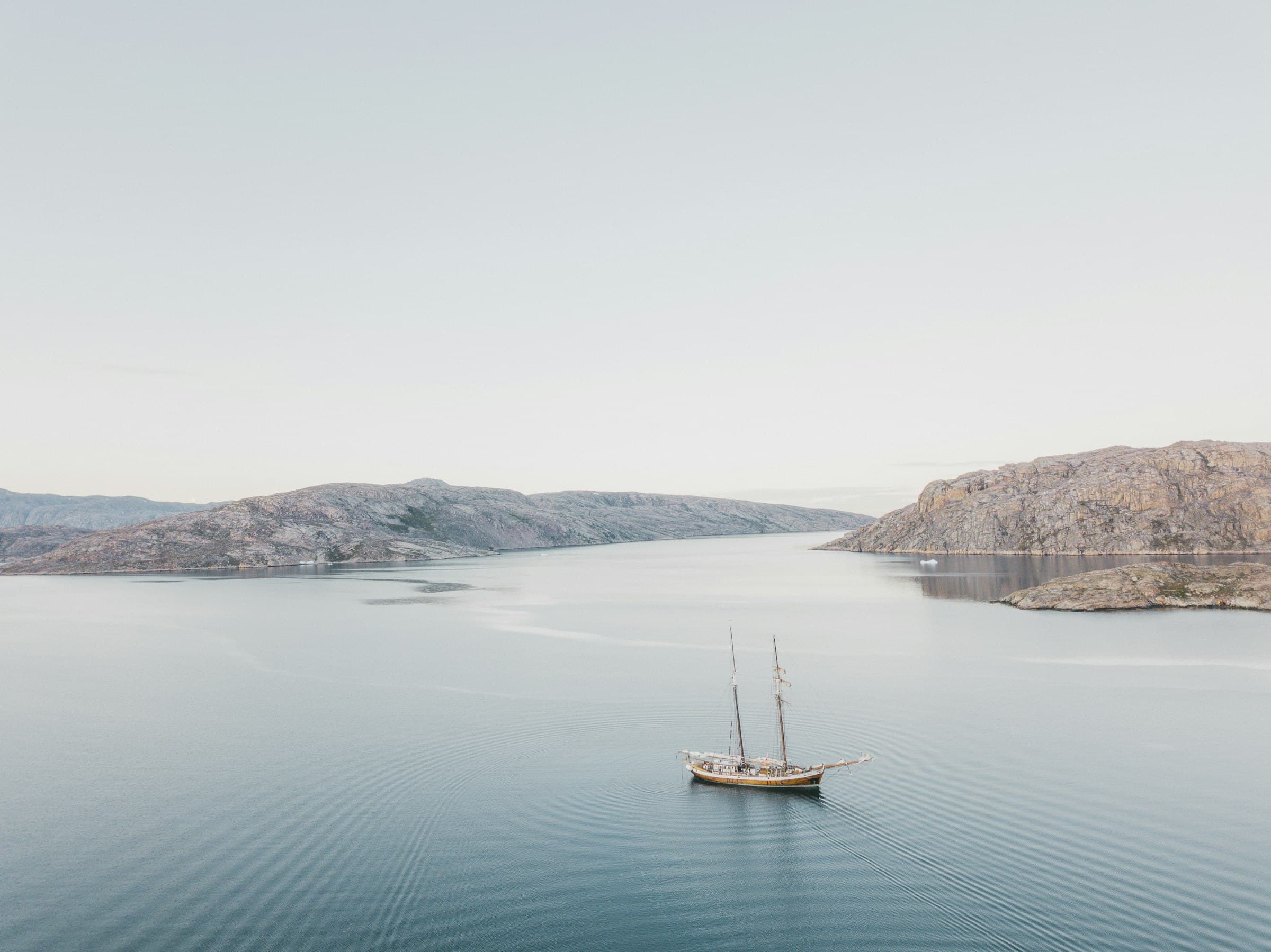 A two-masted sailing boat on a calm fjord